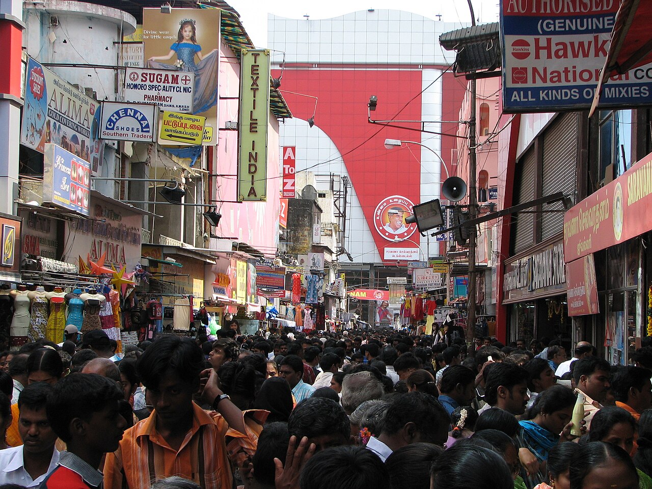 Crowd watching a cricket match on phones in an Indian street