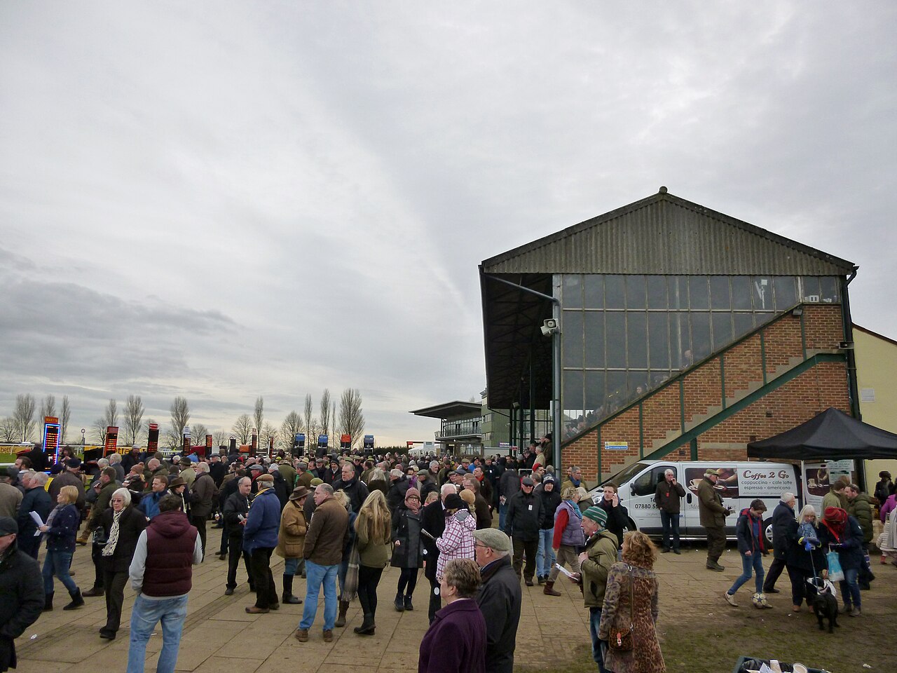 Racegoers along the rail at a city racecourse on a clear winter afternoon
